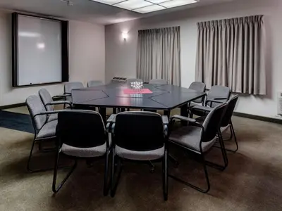 a conference room with a black table and chairs at Heritage Inn Hotel & Convention Centre - Brooks in Brooks