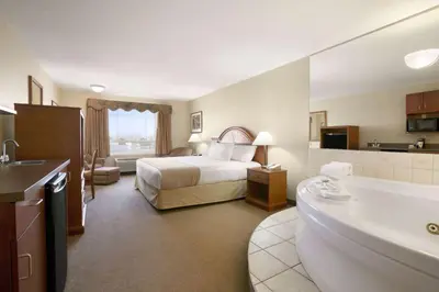 a hotel room with a bed and a bath tub at Super 8 by Wyndham High Level AB in High Level