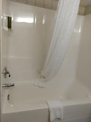 a bathroom with a white tub and a shower curtain at Super 8 by Wyndham High Level AB in High Level
