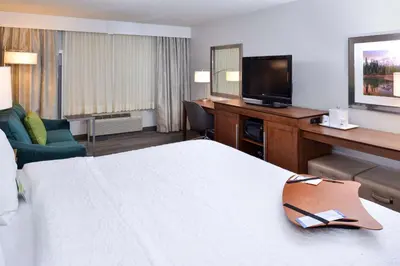 a hotel room with a bed and a desk with a television at Hampton Inn & Suites by Hilton Calgary University NW in Calgary