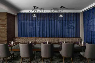 a dining room with a table and chairs and blue curtains at Hilton Garden Inn Calgary Airport in Calgary