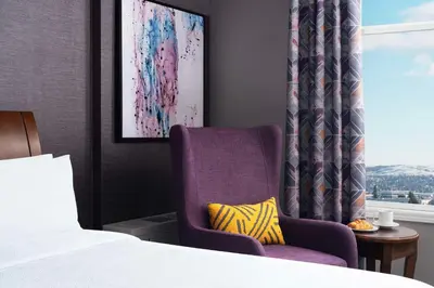 a bedroom with a bed and a chair and a window at Hilton Garden Inn Calgary Airport in Calgary