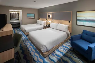 a hotel room with two beds and a blue chair at Accent Inns Kamloops in Kamloops