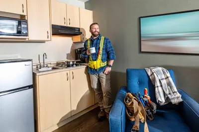 a man is standing in a kitchen with a coffee cup at Accent Inns Kamloops in Kamloops
