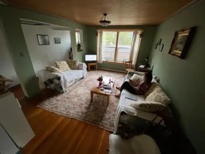 a woman sitting on a couch in a living room at Historic Hotel Bayview in Stewart