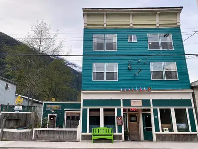 a blue building with a green bench in front of it at Historic Hotel Bayview in Stewart