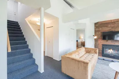 a living room with stairs and a couch and a fireplace at Marquise by Outpost Whistler in Whistler