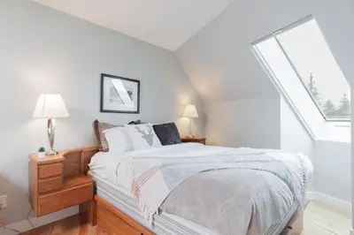 a white bedroom with a bed and a window at Marquise by Outpost Whistler in Whistler