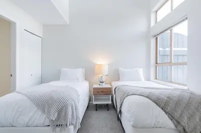two beds in a white room with a window at Tyndall Stone by Outpost Whistler in Whistler