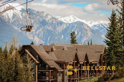 a ski lodge with mountains in the background at Palliser Lodge — Bellstar Hotels & Resorts in Golden