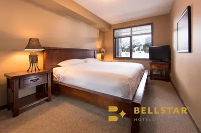 a bedroom with a large bed and a television at Palliser Lodge — Bellstar Hotels & Resorts in Golden