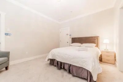 a white bedroom with a bed and a chair at Kim's Place in Surrey
