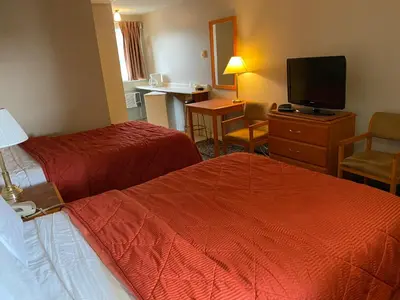 a hotel room with two beds and a flat screen tv at Aspen Motor Inn in Drayton Valley