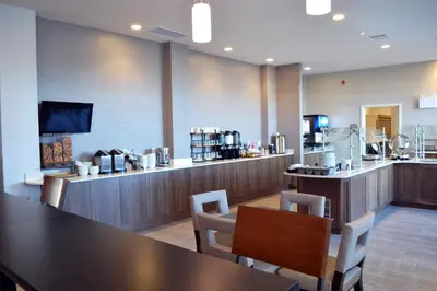 a restaurant with a table and chairs and a bar at Staybridge Suites - Red Deer North by IHG in Red Deer