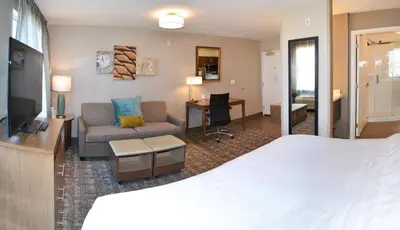 a hotel room with a bed and a desk at Staybridge Suites - Red Deer North by IHG in Red Deer