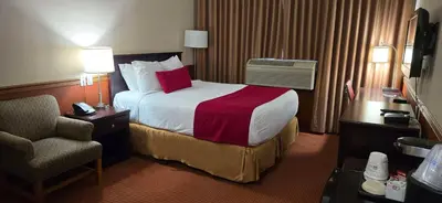 a hotel room with a bed and a chair at SureStay by Best Western Richmond Vancouver Airport in Richmond