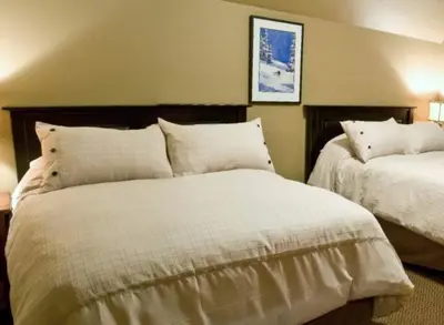 a bedroom with two beds with white sheets at Pinnacle Ridge Chalets by Fernie Lodging Co in Fernie