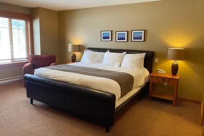 a bedroom with a large bed and a chair at Pinnacle Ridge Condos by Fernie Central Reservations in Fernie