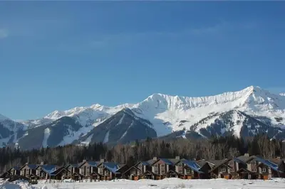 a group of houses in the snow with snow covered mountains at Pinnacle Ridge Condos by Fernie Central Reservations in Fernie
