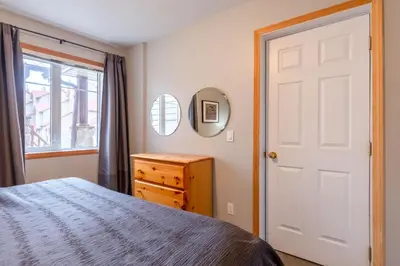 a bedroom with a bed and a mirror and a window at Ski In & 15 Minute Walk to the Lifts Hot Tub AC Pet Friendly in Fernie