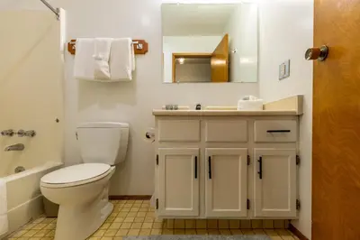 a bathroom with a toilet and a sink and a mirror at Griz Inn by Fernie Central Reservations - Right on The Slopes in Fernie