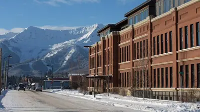a building on a street with a mountain in the background at Luxurious 901 Condos by Fernie Central Reservations in Fernie