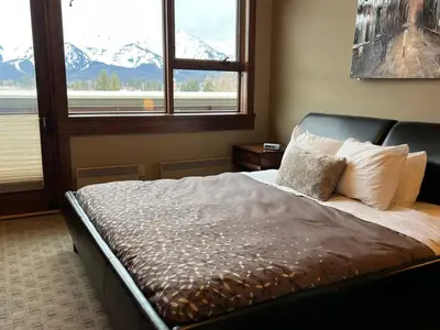 a bed in a bedroom with a view of a mountain at Luxurious 901 Condos by Fernie Central Reservations in Fernie