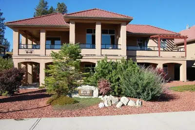a large house with a garden in front of it at A Vacation Paradise at Quail Ridge B&B in Kelowna