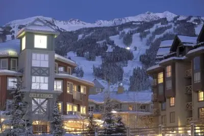 a building with a clock tower in front of a mountain at Studio suite located in the heart of Whistler village in Whistler