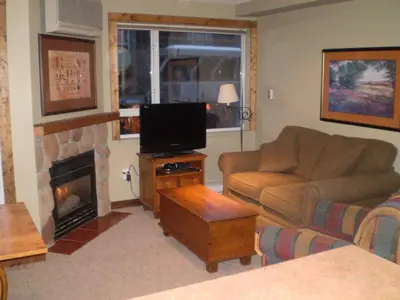 a living room with a couch and a tv and a fireplace at Studio suite located in the heart of Whistler village in Whistler