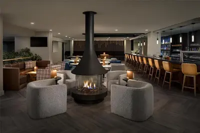 a lobby with a fireplace and chairs and a bar at Hilton Whistler Resort & Spa in Whistler