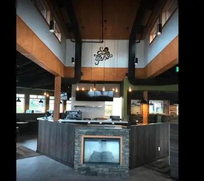a lobby with a fireplace and a television in a building at Arbutus Grove Motel in Parksville