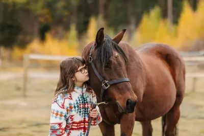 a young girl standing next to a brown horse at Myra Canyon Guest Ranch in Kelowna