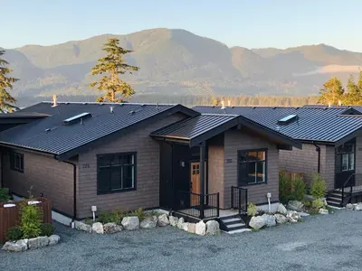 a house with a roof with mountains in the background at Port Renfrew Vacation Rentals in Port Renfrew