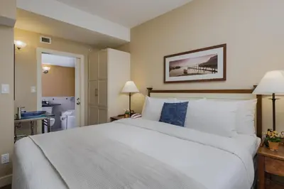 a bedroom with a large white bed and a bathroom at Summerland Waterfront Resort & Spa in Summerland