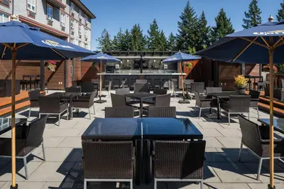 a patio with tables and chairs with umbrellas at Four Points by Sheraton Victoria Gateway in Victoria