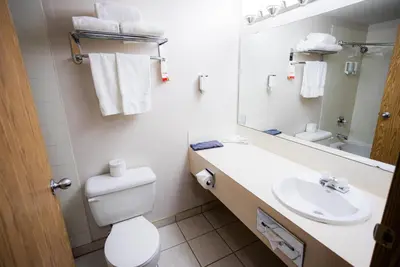 a bathroom with a sink and a toilet and a mirror at Super 8 by Wyndham Drayton Valley in Drayton Valley