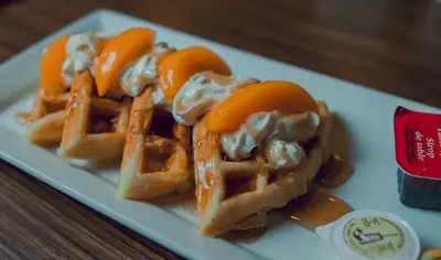 a white plate with waffles and eggs on it at The George Dawson Inn & Conference Centre in Dawson Creek