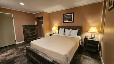 a hotel room with a bed and two lamps at The George Dawson Inn & Conference Centre in Dawson Creek