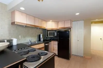 a kitchen with a stove and a black refrigerator at House On Dunbar B&B in Vancouver