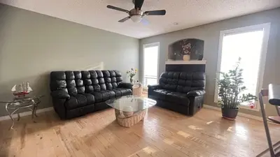 a living room with a black leather couch and a table at Monthly Accommodation Edmonton Londondery, Pilot Sound, McConachie Area in Edmonton