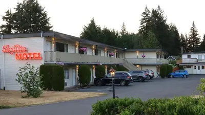 a motel with cars parked in a parking lot at Skylite Motel in Parksville