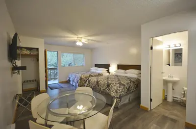 a hotel room with two beds and a glass table at Pender Harbour Resort & Marina in Garden Bay