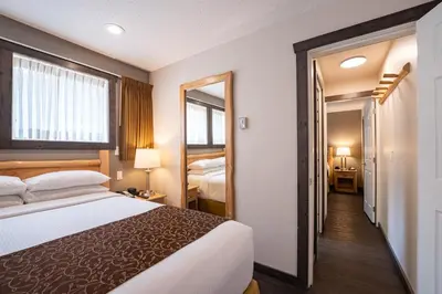 a hotel room with a bed and a mirror at Swiss Chalet Motel in Revelstoke