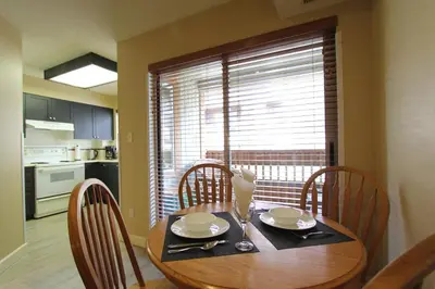 a dining room table with chairs and a kitchen with a window at Marketplace Lodge by Whistler Retreats in Whistler