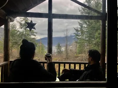 two people sitting on a porch looking out of a window at Morning Star Cabin in Nelson
