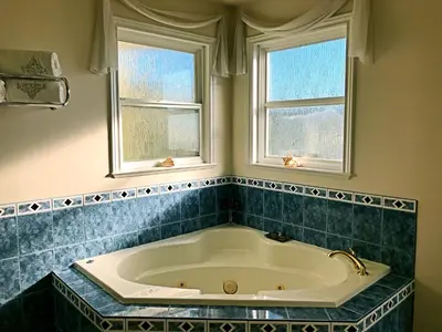 a bath tub in a bathroom with two windows at Star of the Sea guest house in White Rock