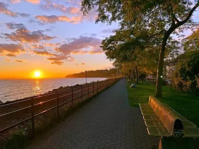 a sidewalk next to a body of water with a sunset at Star of the Sea guest house in White Rock