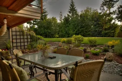 a patio with a table and chairs and a garden at Shawnigan Suite B & B in Shawnigan Lake