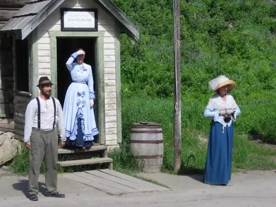 a man and two women standing outside of a small out house at St. George Hotel in Barkerville